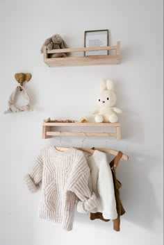 two wooden shelves holding sweaters and stuffed animals on top of them, one is hanging from the wall