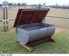 a large metal barrel sitting on top of a wooden stand in the middle of a field