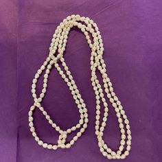 a long white beaded necklace on a purple background