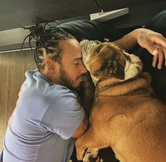 a man laying on the floor next to a large brown dog with dreadlocks