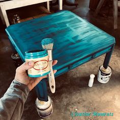 a person holding a paintbrush over a blue table