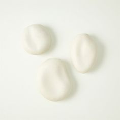 three white rocks sitting on top of a white surface