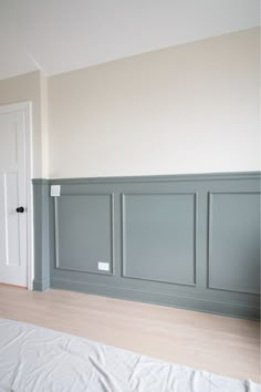 an empty room with wood flooring and walls painted in pale blue, white and beige