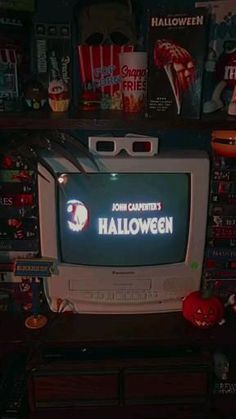 an old television sitting on top of a wooden dresser in front of a wall full of movies