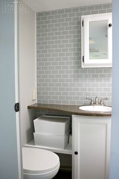 a white toilet sitting next to a sink in a bathroom under a mirror above a vanity