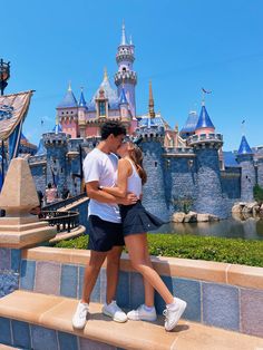 a man and woman are kissing in front of the castle at disneyland california adventure park