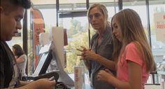 two girls and an older man are looking at something on the table in front of them