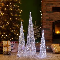 lighted christmas trees in front of a fireplace