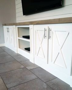 a tv mounted on top of a white cabinet next to a wall with sliding doors