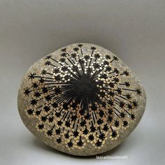 a black and gold vase sitting on top of a rock