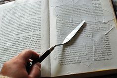 a person is holding a knife and cutting through the pages of a book with scissors