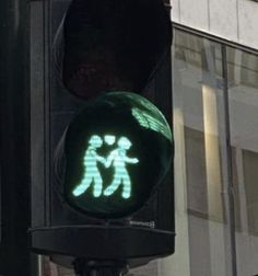 a green traffic light with an image of two people walking on it's crosswalk