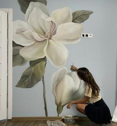 a woman is painting a flower on the wall