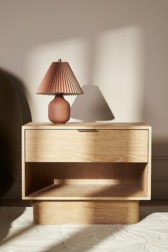 a wooden table with a lamp on it and a bed in the backround