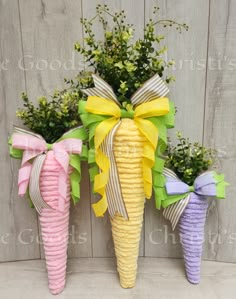 three corn cob vases with flowers and ribbons on the top one is yellow, purple, and green