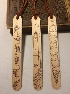 three wooden bookmarks with drawings on them