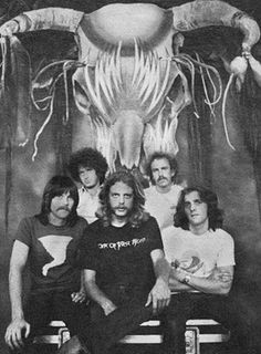 black and white photograph of five people sitting on bench in front of an octopus - like creature