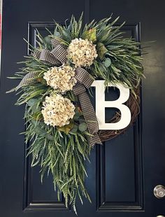 a wreath with the letter b on it is hanging on a black front door,