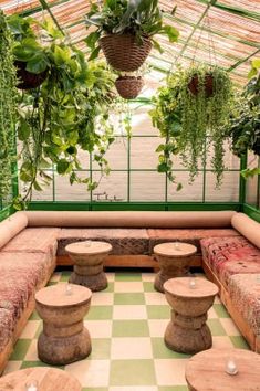 an outdoor seating area with potted plants on the ceiling and benches in the middle