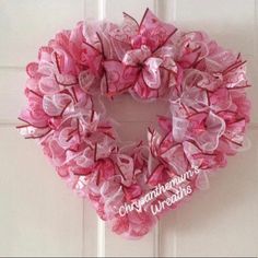 a pink heart shaped wreath hanging on the front door