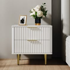 a white chest of drawers with flowers on top