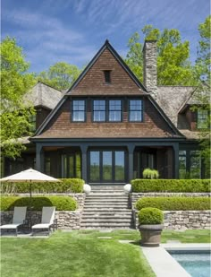 a house with a pool in front of it and an umbrella on the lawn next to it