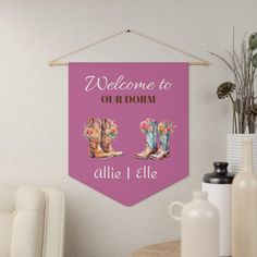 a welcome to our dorm banner hanging on a wall next to a vase with flowers