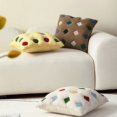 a white couch with two pillows on top of it and a yellow flower in the corner