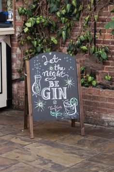 a chalkboard sign sitting in front of a brick wall with ivy growing on it