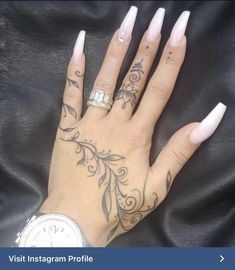 a woman's hand with white nails and tattoos on her left hand, holding a watch