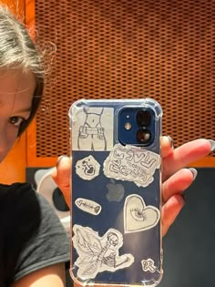 a woman holding up a cell phone case with stickers on it