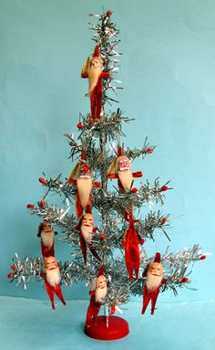 a tinsel christmas tree with santa claus ornaments on it's branches and decorations hanging from the top