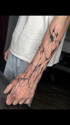 a man's hand with black ink on it and branches coming out of the palm