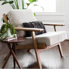 a wooden chair sitting on top of a hard wood floor next to a potted plant