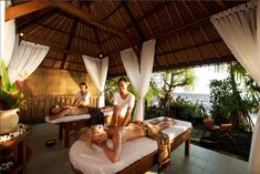 two men are getting massages at the beach in front of an open air pavilion