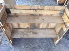 a wooden bench sitting on top of a stone floor next to a table with drawers