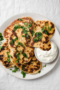 a white plate topped with chicken patties covered in sour cream and garnished with cilantro