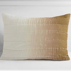 a white and gold pillow sitting on top of a bed