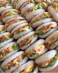 a plate full of sandwiches on buns with cheese and lettuce in them