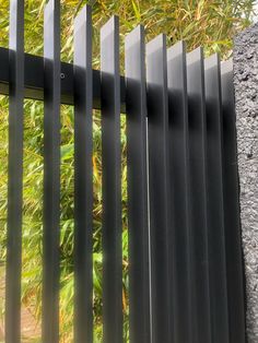 a black metal fence with an arrow pointing to the left and green bushes in the background