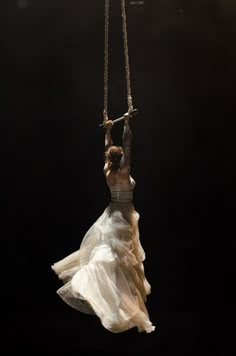 a woman in white dress swinging on a rope