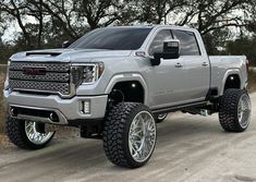 a silver truck parked on the side of a dirt road next to some grass and trees