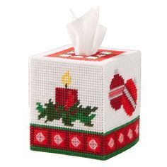 a tissue box with a candle and holly design on the front is decorated in red, green, and white