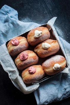 a bunch of doughnuts sitting in a box on top of a blue napkin