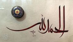 an arabic calligraphy is displayed on a white surface with a blue and red object