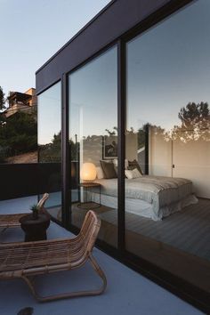 a bed sitting on top of a wooden floor next to a glass wall covered in windows