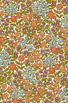 an orange, blue and green floral pattern on white fabric with small flowers in the center