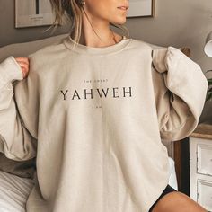 Cozy up in this Yahweh The Great I Am sweatshirt. It's a perfect way to express your faith. This stylish piece will be sure to become your go-to hoodie this season. Made from premium materials, it's designed to be comfortable and keep you warm all day long. So spread the good word and grab this christian sweatshirt today! ♥ All shirts from Diligently Devoted are handmade-to-order, just for you!  ♥CLOTHING MATERIAL * Bella And Canvas Brand for T- shirts and Gildan Brand for Sweatshirts & Hoodies * Rolled up sleeves in picture is for styling purpose only * Props used in the photos are not included with purchase * 50% pre-shrunk cotton, 50% polyester * Fabric weight: 8.0 oz/yd² (271.25 g/m²) * Air-jet spun yarn with a soft feel and reduced pilling * Double-lined hood with matching drawcord * Yahweh Shirt, Sweatshirt Design Ideas, Jesus Sweatshirts, Christian Hoodies, Clothing Material, Christian Sweatshirt, Roll Up Sleeves, Christian Clothing, Unisex Shirts