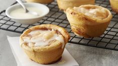 some kind of pastry sitting on top of a cooling rack next to a bowl of cream