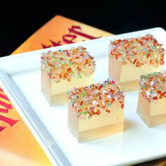 three pieces of cake on a white plate with colorful sprinkles around it